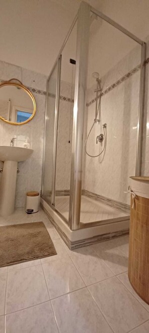 Ein Badezimmer mit Duschkabine, Waschbecken und Spiegel.