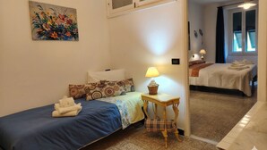 A bedroom with a single bed, a bedside table with a lamp, and a chair. - Charming Apartment in Vernazza IT011030C25E7RWJXG (Vernazza)