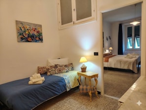 Ein Schlafzimmer mit einem Einzelbett, einem Nachttisch mit Lampe und einem Sessel.