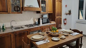 A kitchen with wooden cabinets, a gas stove, and a dining table set for four. - Charming Apartment in Vernazza IT011030C25E7RWJXG (Vernazza)