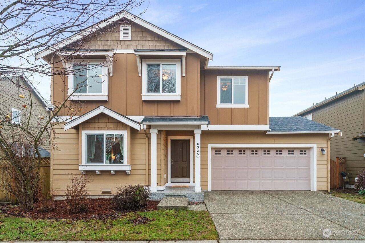 A two-story house with a front garage, a front door, and a small front yard.