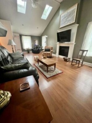 A living room with a sofa, a coffee table, a fireplace, and a television. - Spacious 4-Bedroom Pet-Friendly Home Near Antietam & Historic Sharpsburg (Sharpsburg)