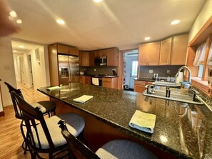 Una cocina moderna con una isla grande, electrodomésticos de acero inoxidable y armarios de madera.