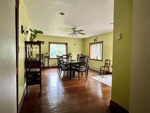 A dining area with a wooden table and chairs, a ceiling fan, and windows with blinds. - Spacious 4-Bedroom Pet-Friendly Home Near Antietam & Historic Sharpsburg (Sharpsburg)