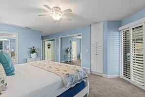 Un dormitorio con cama, ventilador de techo, armario y ventana con persianas.