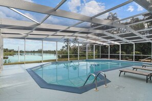 Una piscina interior con techo de vidrio, rodeada de sillones de descanso y vistas a un paisaje natural.