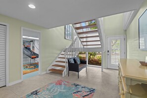 Eine Treppe führt zu einer zweiten Etage, ein Essbereich mit Tisch und Stühlen und ein Basketballkorb im Hintergrund.