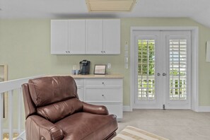 Ein Zimmer mit einem braunen Ledersofa, weißen Schränken, einer Kaffeemaschine und einer Tür mit Gittermuster.