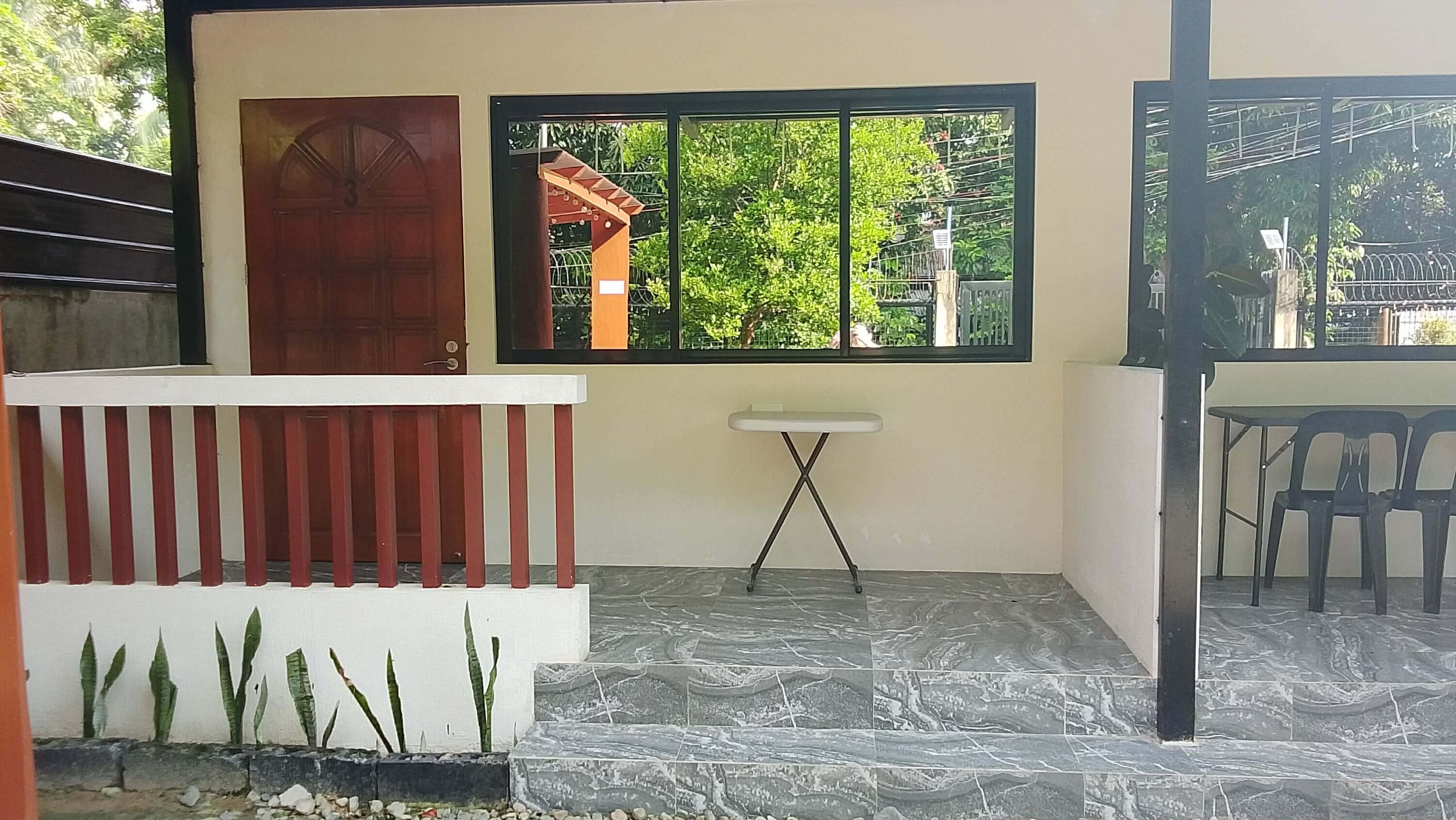 Una habitación con puerta, ventana, una pequeña mesa y zona de estar.