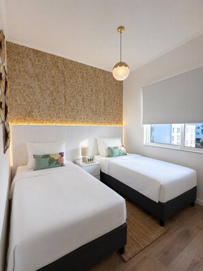 Ein Hotelzimmer mit zwei Betten, einem großen Fenster und einer Wand mit Muster.
