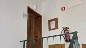 Una escalera con barandilla de metal, una puerta de madera y un extintor de incendios en la pared.