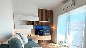 Una sala de estar moderna con un sofá, un televisor de pantalla plana y un control remoto sobre una mesa.