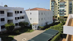 Zona residencial con edificios de varios pisos, un patio empedrado y un vehículo estacionado.