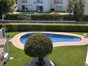 Ein Pool mit kreisförmigem Design, umgeben von einer gepflasterten Terrasse und einem gepflegten Heckenstreifen.