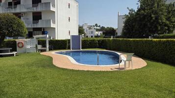 Une piscine entourée d’une pelouse bien entretenue, avec un bâtiment en arrière-plan.