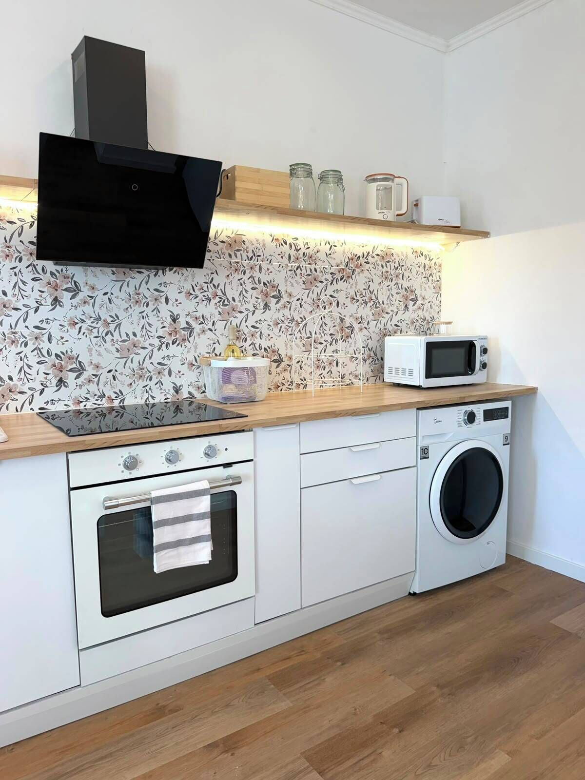 A compact kitchen with a microwave, oven, and washing machine.