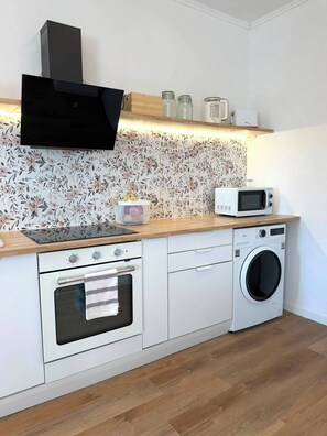 Eine kleine Küche mit Mikrowelle, Backofen und Waschmaschine.