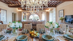 A dining area with a chandelier, upholstered chairs, and a table set for a meal. - Villa Near Lucca With Private Pool (Lucca)