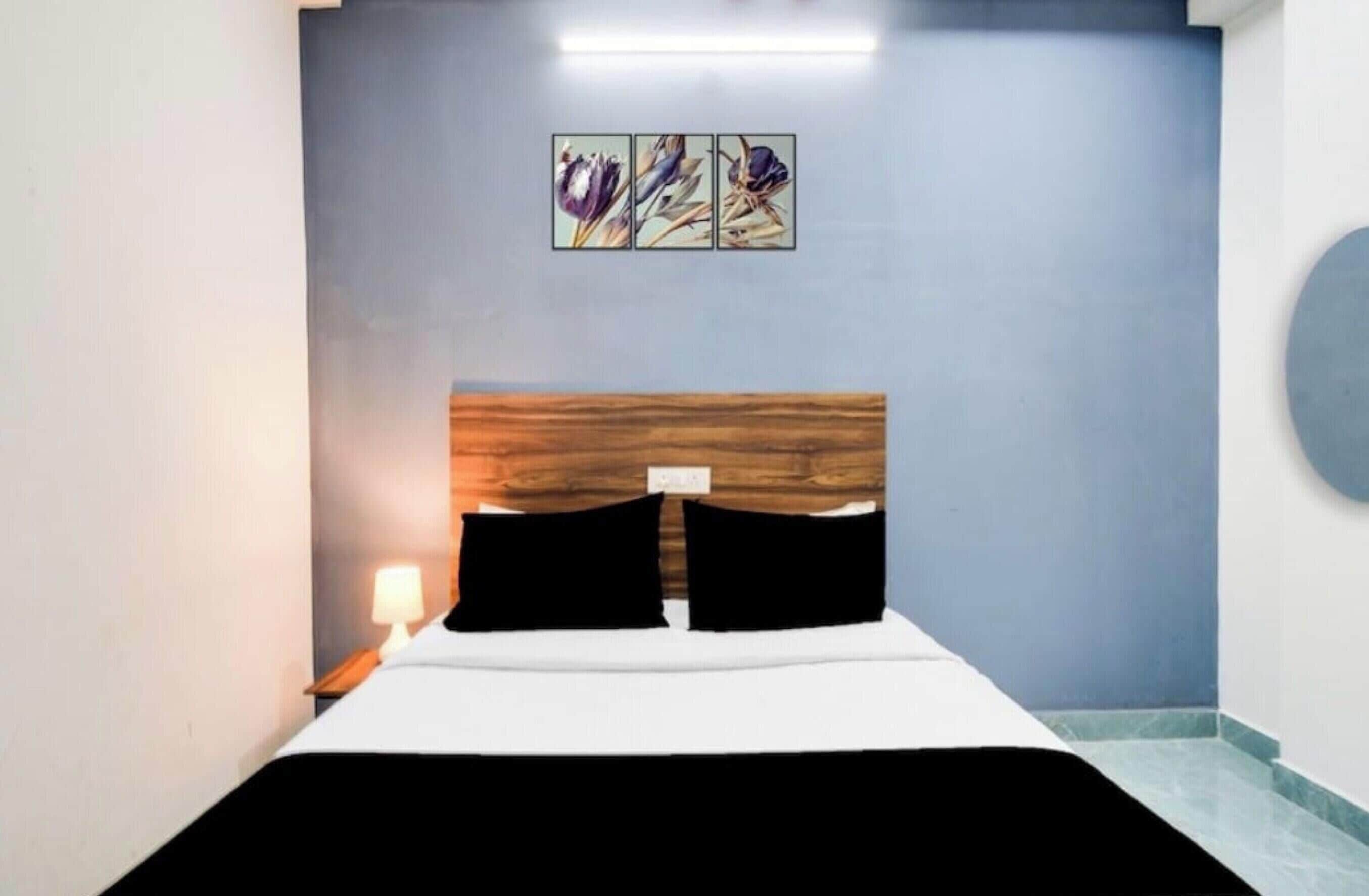 Une chambre d’hôtel comprenant un lit, une table de chevet, une lampe et une œuvre d’art accrochée au mur.