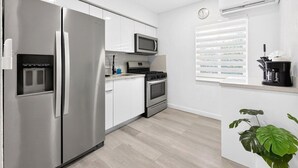 Una cocina moderna con un refrigerador de acero inoxidable, microondas y estufa a gas.