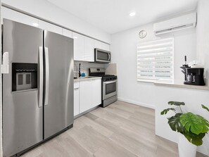 Eine moderne Küche mit einem Edelstahl-Kühlschrank, einer Mikrowelle und einem Gasherd.