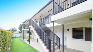 Un edificio moderno con una escalera que conduce a un balcón, un césped bien cuidado y un cielo despejado.