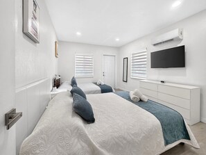 Een hotelkamer met een groot bed, een nachtkastje, een televisie en een airconditioner.