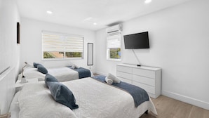 A bedroom with two beds, a TV, and a dresser. - Modern Miami Stay - Near Airport & Downtown (Miami)