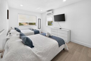 A bedroom with two beds, a TV, and a dresser. - Modern Miami Stay - Near Airport & Downtown (Miami)