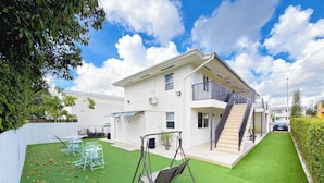 A modern two-story house with a balcony, a swing set, and a well-maintained lawn. - Modern Miami Stay - Near Airport & Downtown (Miami)