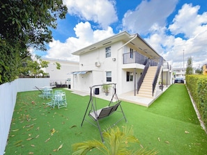 A modern two-story house with a balcony, a swing set, and a well-maintained lawn. - Modern Miami Stay - Near Airport & Downtown (Miami)