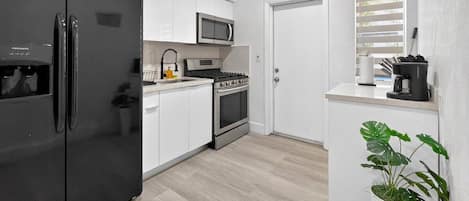 A modern kitchen with a refrigerator, stove, microwave, and sink.
