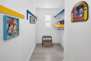 A hallway with a framed picture, a door, a basket, and a wall sign. - Modern Miami Stay - Near Airport & Downtown (Miami)