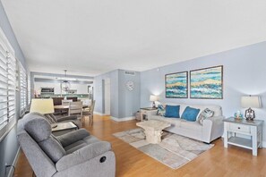 A modern living room with a grey sofa set, a coffee table, and artwork on the wall. - 2BR Near Beach • Pool • BBQ • Parking (Fort Lauderdale)