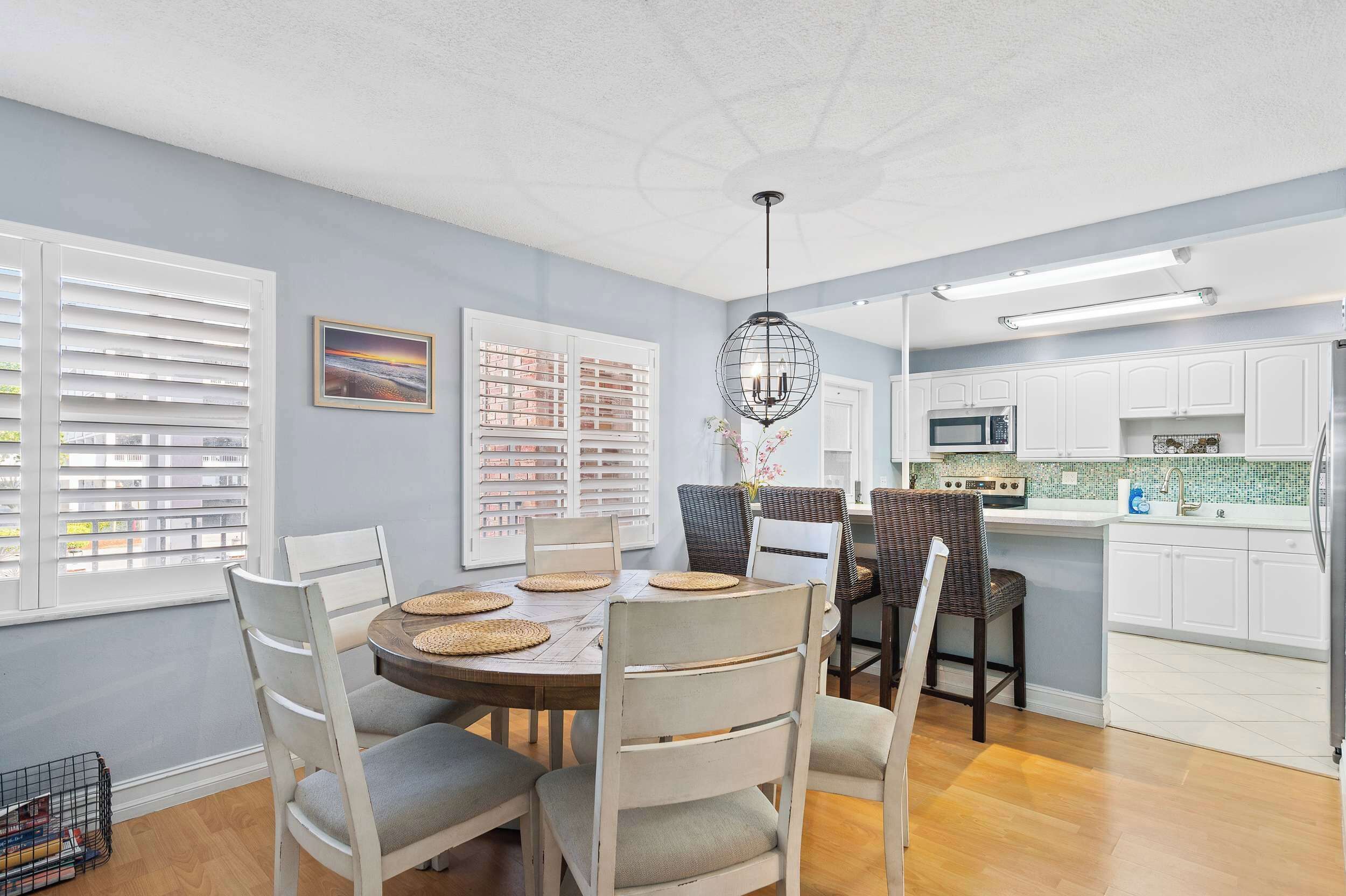 A dining area with a round table, chairs, and a hanging light fixture.