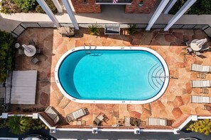 Una piscina exterior amb terrassa de pedra, envoltada de gandules i ombrel·les.