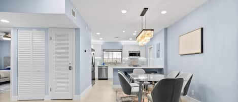 A modern kitchen with white cabinets, a stainless steel refrigerator, and a built-in oven.