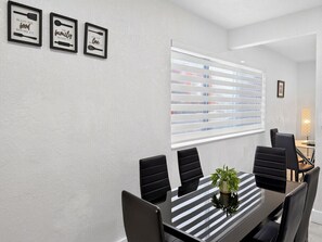 A conference room with a long table, black chairs, a potted plant, and three framed inspirational quotes on the wall. - Renovated 2BR Miami Apt Near MIA with Parking (Miami)