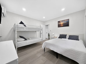 Een slaapkamer met stapelbedden, een eenpersoonsbed, een bureau en een nachtkastje.