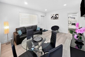 A modern living room with a glass coffee table, black leather sofa, and a black armchair. - Renovated 2BR Miami Apt Near MIA with Parking (Miami)