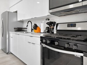 A modern kitchen with a stainless steel refrigerator, a built-in oven, and a gas stove. - Renovated 2BR Miami Apt Near MIA with Parking (Miami)