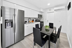 A modern kitchen with stainless steel appliances, a dining table with chairs, and a microwave above the counter. - Renovated 2BR Miami Apt Near MIA with Parking (Miami)