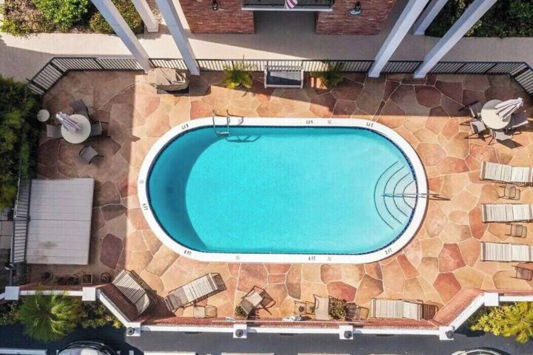 A rooftop swimming pool with a stone deck, surrounded by lounge chairs and umbrellas.