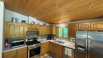 A kitchen with wooden cabinets, a stainless steel refrigerator, a stove, and a microwave.