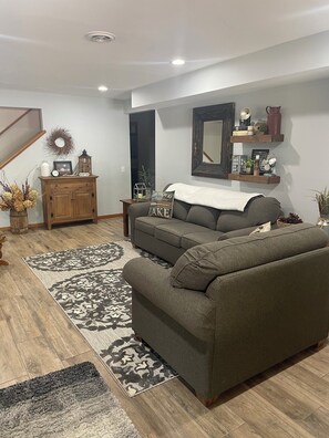 Ein Wohnzimmer mit einer Couch, einem Holzschrank, einem Teppich und einem Spiegel an der Wand.