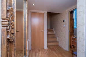 Ein Flur mit Holzboden, einer Holztür und einer Treppe, die in einen anderen Raum führt.