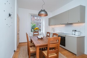 A modern kitchen with a dining table, chairs, and a pendant light. - Leith City Escape - Stylish 2BR Apartment - Pass the Keys (Edinburgh)