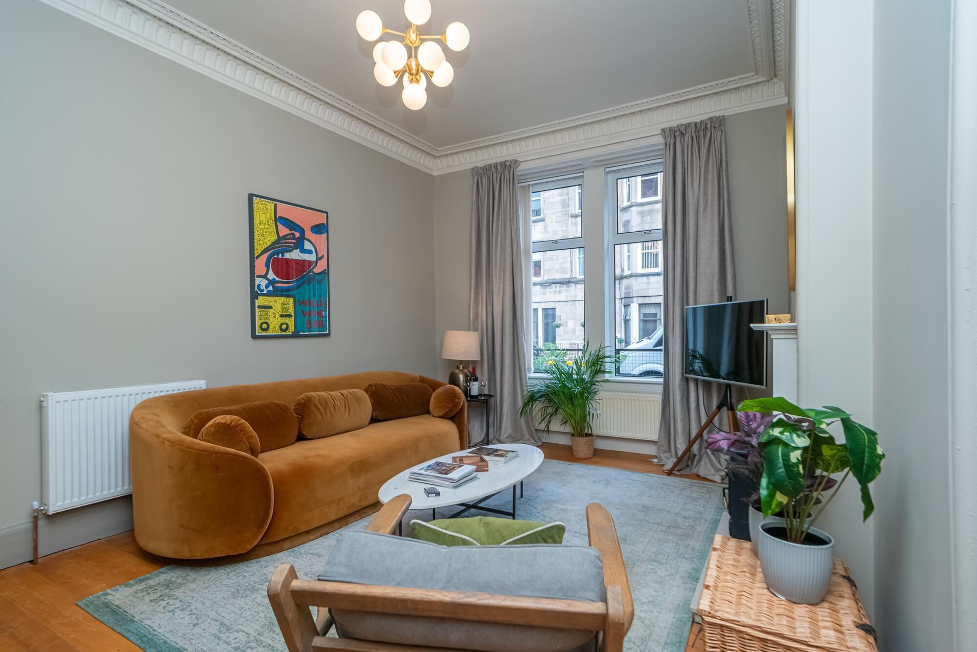 A living room with a sofa, a coffee table, a TV, and a window with curtains.