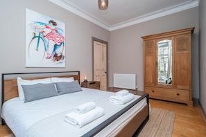 A bedroom with a bed, a nightstand, a wooden wardrobe, and a painting on the wall. - Leith City Escape - Stylish 2BR Apartment - Pass the Keys (Edinburgh)