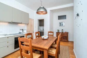 A modern kitchen with white cabinets, a wooden dining table, and a hanging pendant light. - Leith City Escape - Stylish 2BR Apartment - Pass the Keys (Edinburgh)